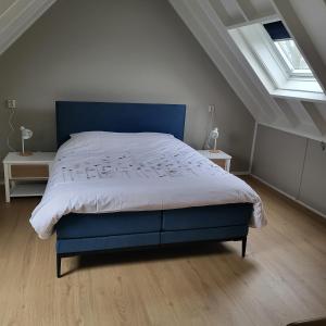 a bedroom with a blue bed in a attic at Aan `t Krakeel in Noordscheschut