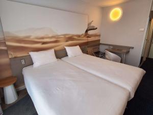 a bedroom with a large white bed with a painting on the wall at ibis Styles Toulon Centre Port in Toulon