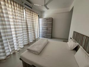 a bedroom with a bed with curtains and a window at Triveni Stays 5 BHK Pure Veg Villa in Lonavala in Kārli