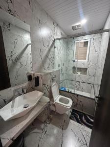 a marble bathroom with a sink and a toilet at Triveni Stays 5 BHK Pure Veg Villa in Lonavala in Kārli