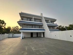 a large white building with a fence in front of it at Triveni Stays 5 BHK Pure Veg Villa in Lonavala in Kārli