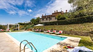 a swimming pool with chairs and a house in the background at Lovely 6 bed Tuscan Farmhouse in Villamagna