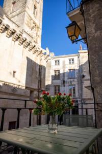 a vase with red flowers sitting on a table in front of a building at Le Banksy hyper centre avec terrasse in Niort