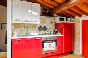 a red kitchen with a sink and a stove at Mansarda nel Cuore di Pisa in Pisa