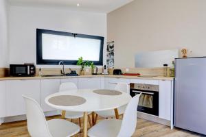 cocina con mesa blanca y sillas blancas en L'écrin salé, en Étang-Salé