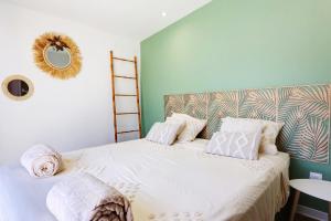 Un dormitorio con una cama con sábanas blancas y un espejo. en L'écrin salé, en Étang-Salé