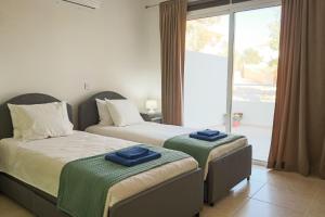a bedroom with two beds with blue towels on them at Nissi Elena -Sunshine Apt in Ayia Napa +73 photos