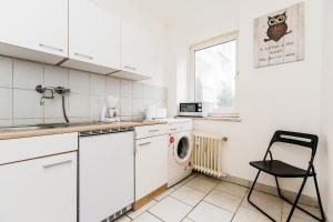 a white kitchen with a washing machine and a chair at Work & Stay apartments Solingen in Solingen +23 photos