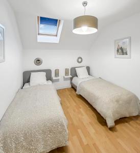 two beds in a room with white walls and wooden floors at Les Cottages Honfleur in La Rivière Saint Sauveur +12 photos