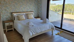 a bedroom with a bed with white sheets and a balcony at Casa con piscina Sanxenxo in Pontevedra +15 photos