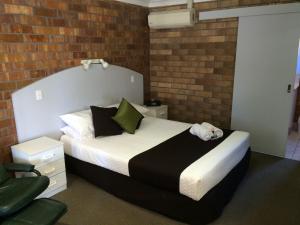 a bedroom with a bed and a brick wall at Miles Outback Motel in Miles