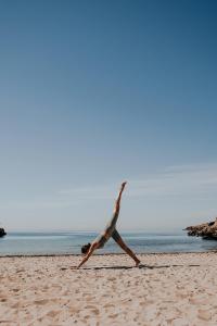 Una mujer haciendo un puesto de manos en la playa en The Donna Portals, en Portals Nous