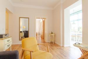 a living room with a yellow chair and a mirror at 2 Meerestraum in Rostock