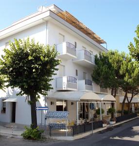 een groot wit gebouw met bomen ervoor bij Hotel Lora in Rimini