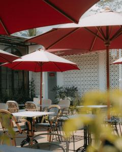 a patio with tables and chairs with red umbrellas at Van Bloemen 1881 Resort in Kembanglimus