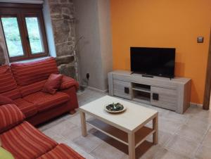a living room with a red couch and a flat screen tv at Casa Alicia in Carnota