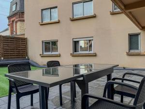 a glass table and chairs in front of a building at Villa Bel Air - appartement avec jardin et parking in Chartres
