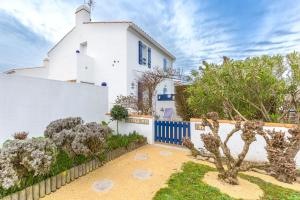 a white house with a blue fence and trees at Le Nid de Noirmoutier - A 300m du port in Noirmoutier-en-l'lle