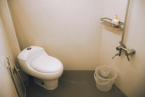 a small bathroom with a toilet and a trash can at Naksha Tree Hotels Kishore Inn - Koyambedu in Chennai +25 photos