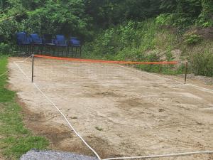 a tennis net on a dirt court with chairs at Ganghwado Baba Valley Pension in Incheon