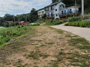a dirt road with a house in the background at Ganghwado Baba Valley Pension in Incheon +37 photos