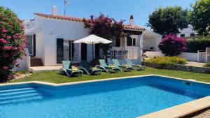 a house with a swimming pool with chairs and an umbrella at Villa Cristina in Binibeca
