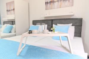a white coffee table with cups on a bed at DANESTRA Sokobanja in Soko Banja