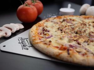 a pizza sitting on top of a table with tomatoes at ibis Paris Montmartre Sacré-Coeur in Paris