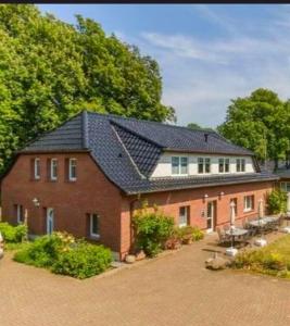 a large red brick house with a black roof at Ferienhaus BODDEN- vis-a-vis Hiddensee für bis zu 15 Gäste in 7 Appartements in Schaprode