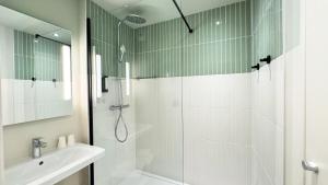 a white bathroom with a shower and a sink at Kyriad Prestige Compiègne Hotel & Spa in Compiègne