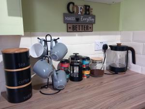 a kitchen counter with cups and coffee makers on it at Douglas Apartment - Trains to Edin & Glasgow - Private Parking in Airdrie