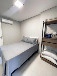 - une chambre avec un lit et une étagère avec des serviettes dans l'établissement Refúgio Perfeito no Boqueirão: Apartamento Moderno a 100m da Praia com Sacada Gourmet e Piscina!, à Praia Grande