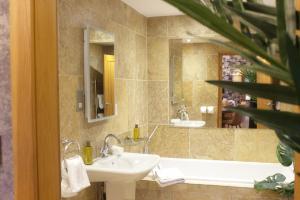 a bathroom with a sink and a tub and a mirror at Norway Spruce Lodge - The Hollies Retreats in Oakmere +13 photos