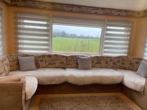 a couch in a living room with a large window at Caravan 5 by The River Severn, dog friendly, great for contractors, walkers and fishing on the river in Chaceley