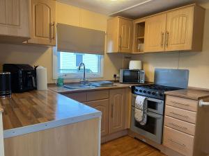 a kitchen with wooden cabinets and a stove top oven at Caravan 5 by The River Severn, dog friendly, great for contractors, walkers and fishing on the river in Chaceley