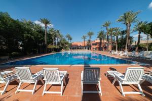 a swimming pool with lounge chairs and palm trees at Las Palmeras in Crevillente
