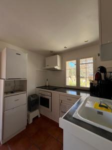 PuyloubierにあるStudio au Pied de la ste Victoireの白いキャビネットとシンクのあるキッチン