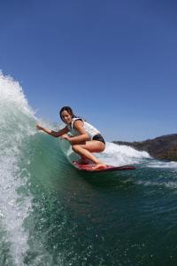 a woman riding a wave on a surfboard in the ocean at Canto do Zêzere, Sertã, Dornes, Castelo do Bode in Cernache do Bonjardim