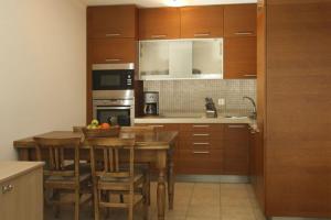 una cocina con armarios de madera y una mesa con sillas. en Residenz Ambassador A32 en Leukerbad