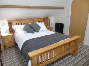 sypialnia z dużym drewnianym łóżkiem z poduszkami w obiekcie Kings Head w mieście Capel Hendre