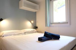 - un lit blanc avec un sac bleu assis dans l'établissement Happy Camp Mobile Homes in Camping Le Domaine La Yole, à Vendres 16 autres photos