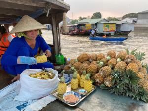a woman standing next to a table full of pineapples at Miền Tây Hotel in Can Tho