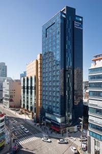 wysoki szklany budynek w mieście z samochodami w obiekcie Benikea Hotel Haeundae w Pusanie