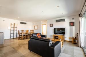 uma sala de estar com um sofá preto e uma TV em Sunset T3 - by Smarthomes em São Martinho do Porto