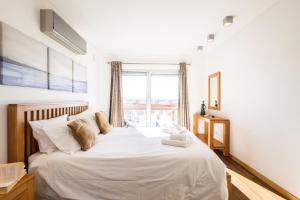 um quarto com uma grande cama branca e uma janela em Sunset T3 - by Smarthomes em São Martinho do Porto mais 32 fotografias