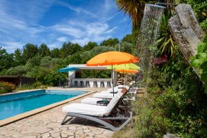 a group of chairs with umbrellas next to a pool at Dépendance d'un mas provençal in Solliès-Pont