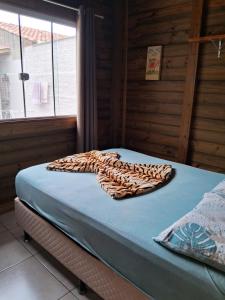 a bed with a leopard blanket on top of it at Chalés Lar Doce Mar Camacho SC in Jaguaruna