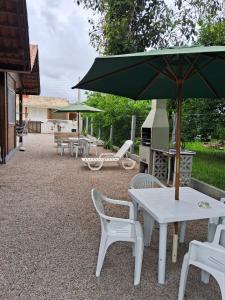 a table and chairs with an umbrella and a grill at Chalés Lar Doce Mar Camacho SC in Jaguaruna