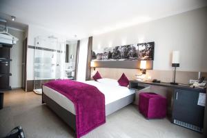 ein Schlafzimmer mit einem großen Bett mit einer lila Decke in der Unterkunft Amalienburg - Boutique & Boarding Hotel in München
