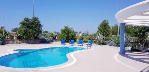 a swimming pool with blue chairs and a umbrella at Villa Mavi Çalis in Fethiye